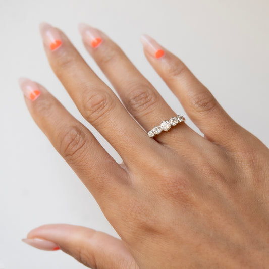 Hand wearing a diamond ring with a neutral background