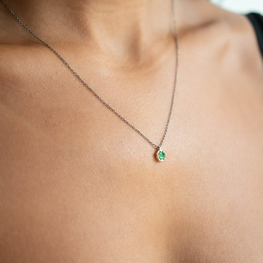 Emerald pendant set in gold on an oxidized silver chain on person