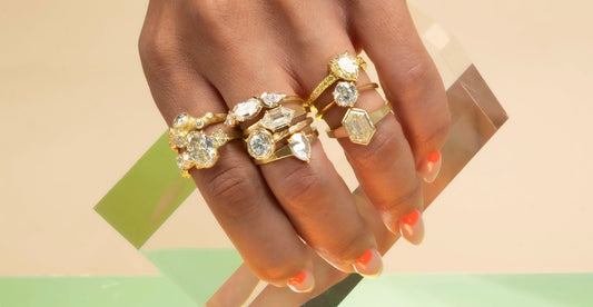 many diamond and gold engagement rings shown on hand model