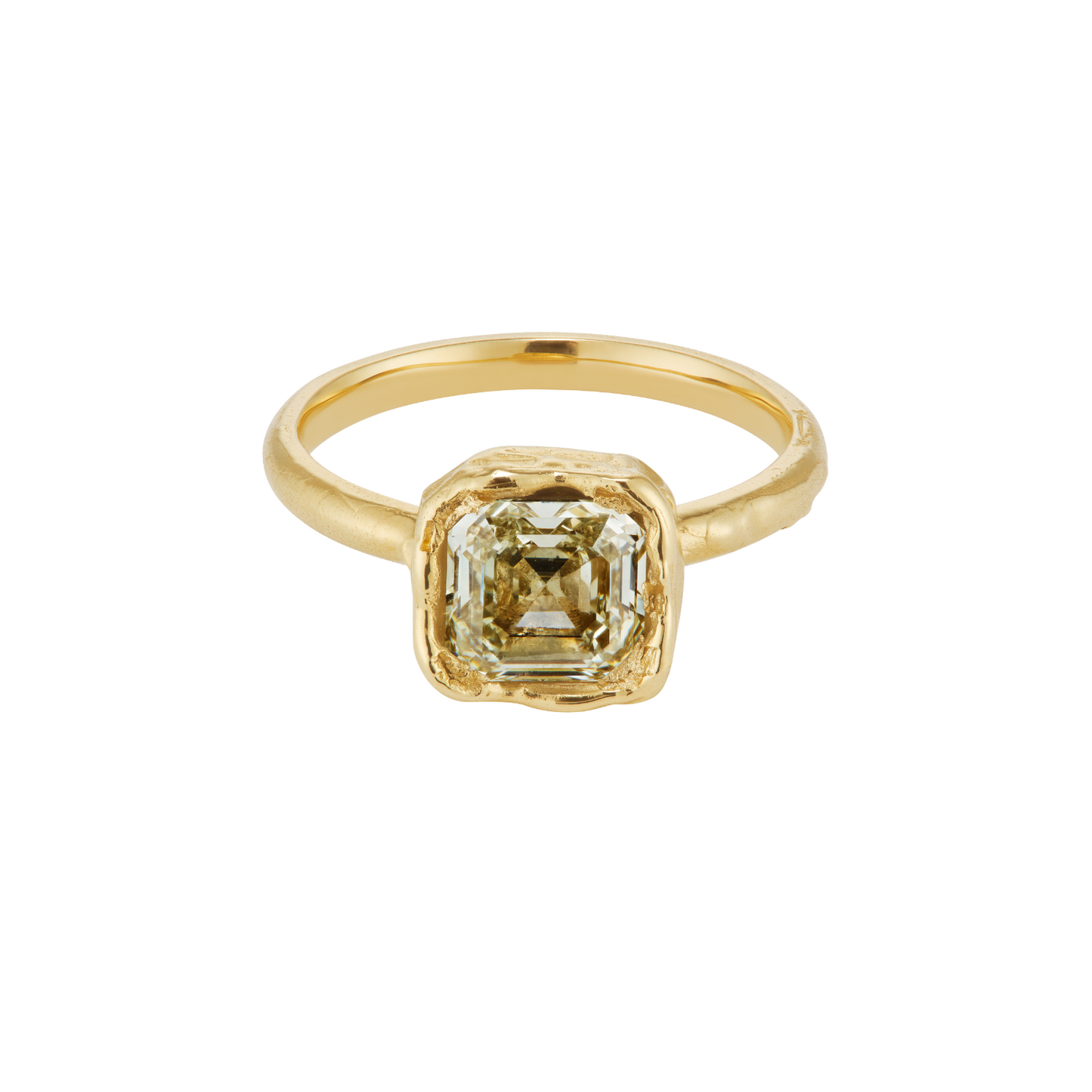 A gold ring featuring a square-cut, emerald-shaped clear gemstone in a textured bezel setting, shown on a plain white background.