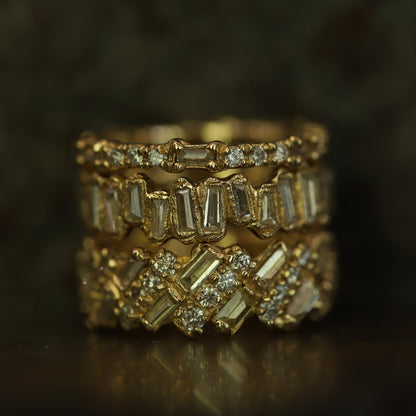 Ellis Mhairi Cameron - Stack of gold rings with diamond accents on a dark background
