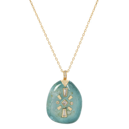 Tourmaline pendant with gold accents on a gold chain against a white background