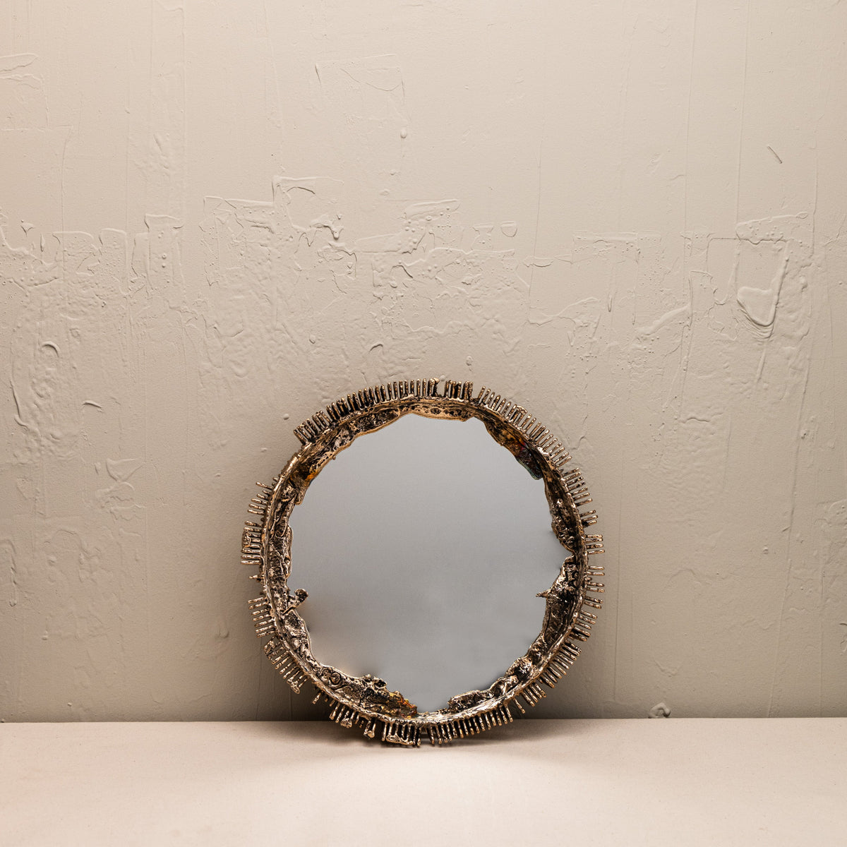 Round mirror with decorative frame on a beige surface and wall