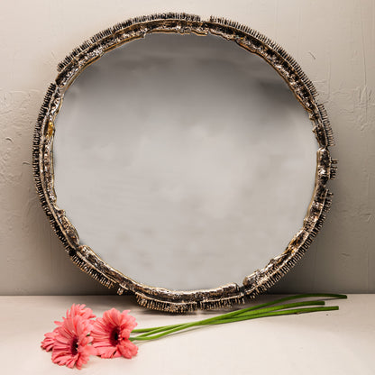 Round decorative mirror with a textured frame on a neutral background with pink flowers.