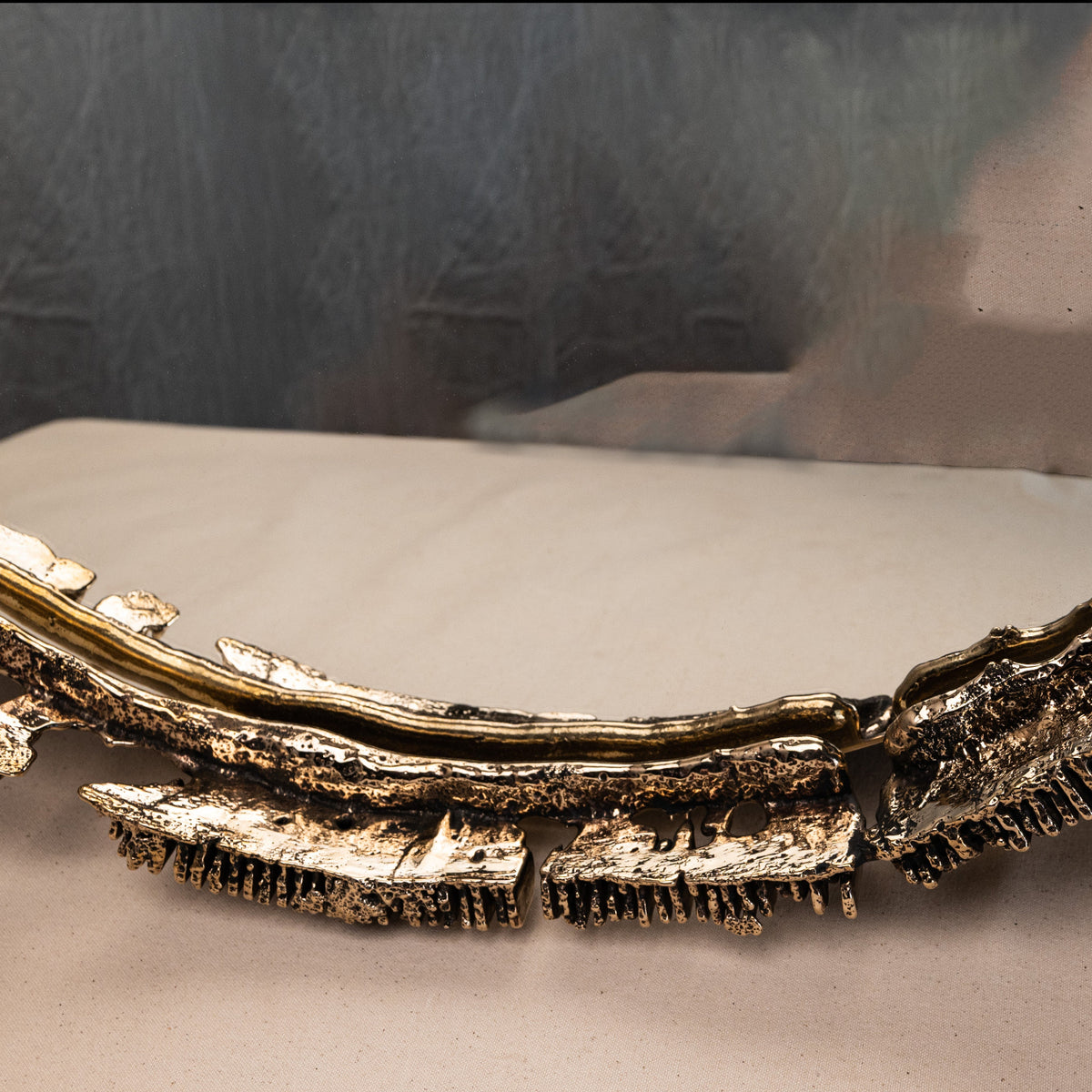 Decorative gold mirror with intricate design on a neutral background