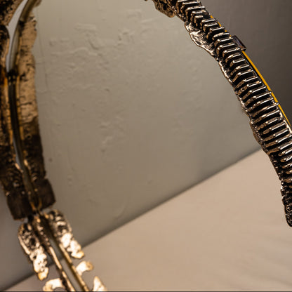 Close-up of a decorative mirror with intricate design on a plain background