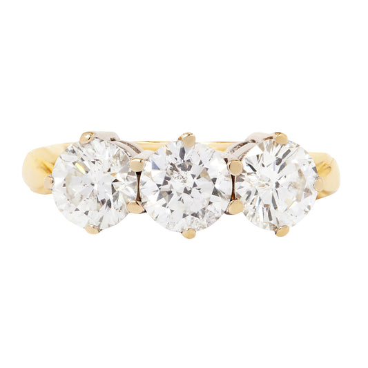 Gold ring with three clear gemstones on a white background