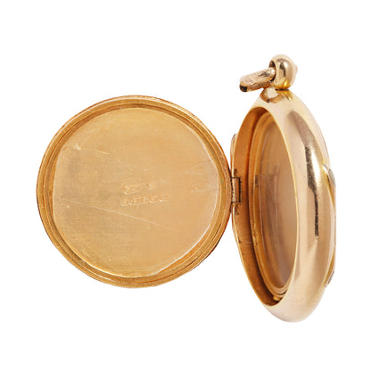 An open round gold locket pendant, showing the polished inner surfaces and a small top loop, photographed on a plain white background.