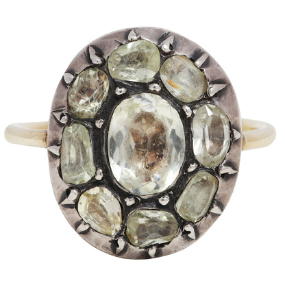 Antique ring with central gemstone and smaller green stones on a white background