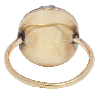 Antique ring with central gemstone and smaller green stones on a white background