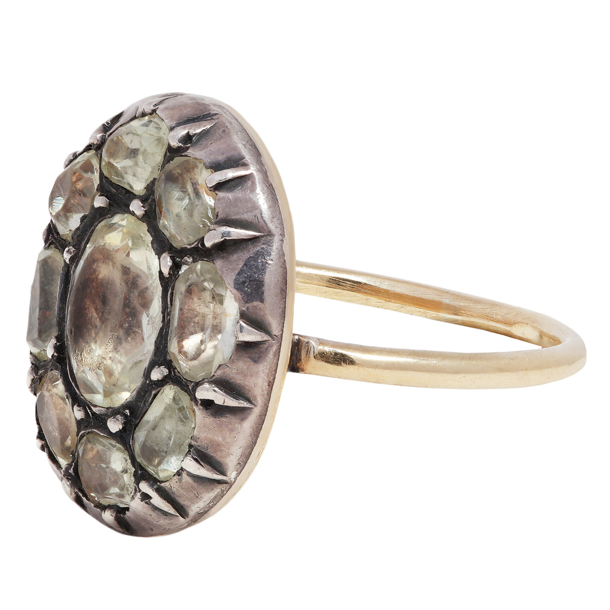 Antique ring with central gemstone and smaller green stones on a white background