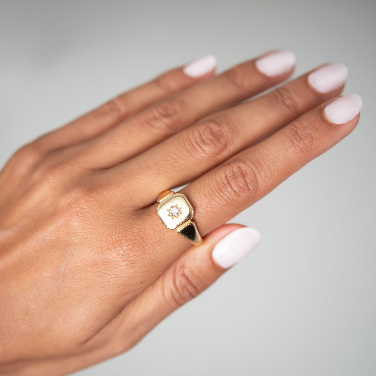 Antique - Hand wearing a gold ring with a diamond on a gray background