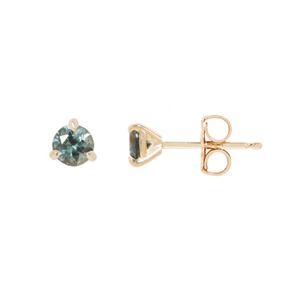two small gold stud earrings with blue sapphires, against a white background.