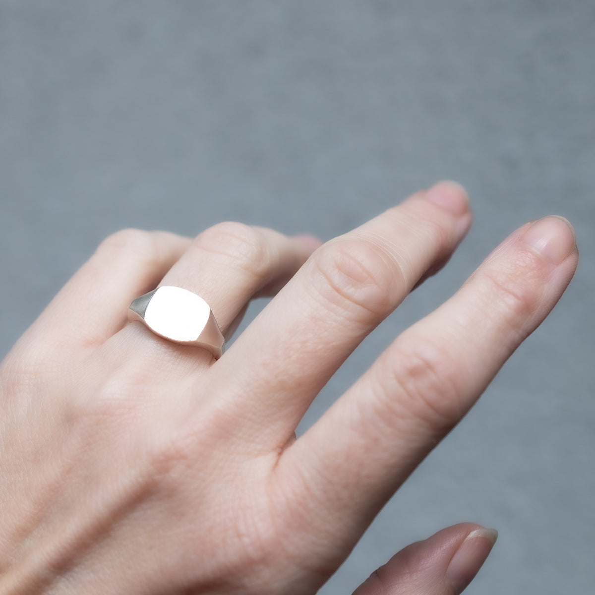 Silver square ring on a hand.