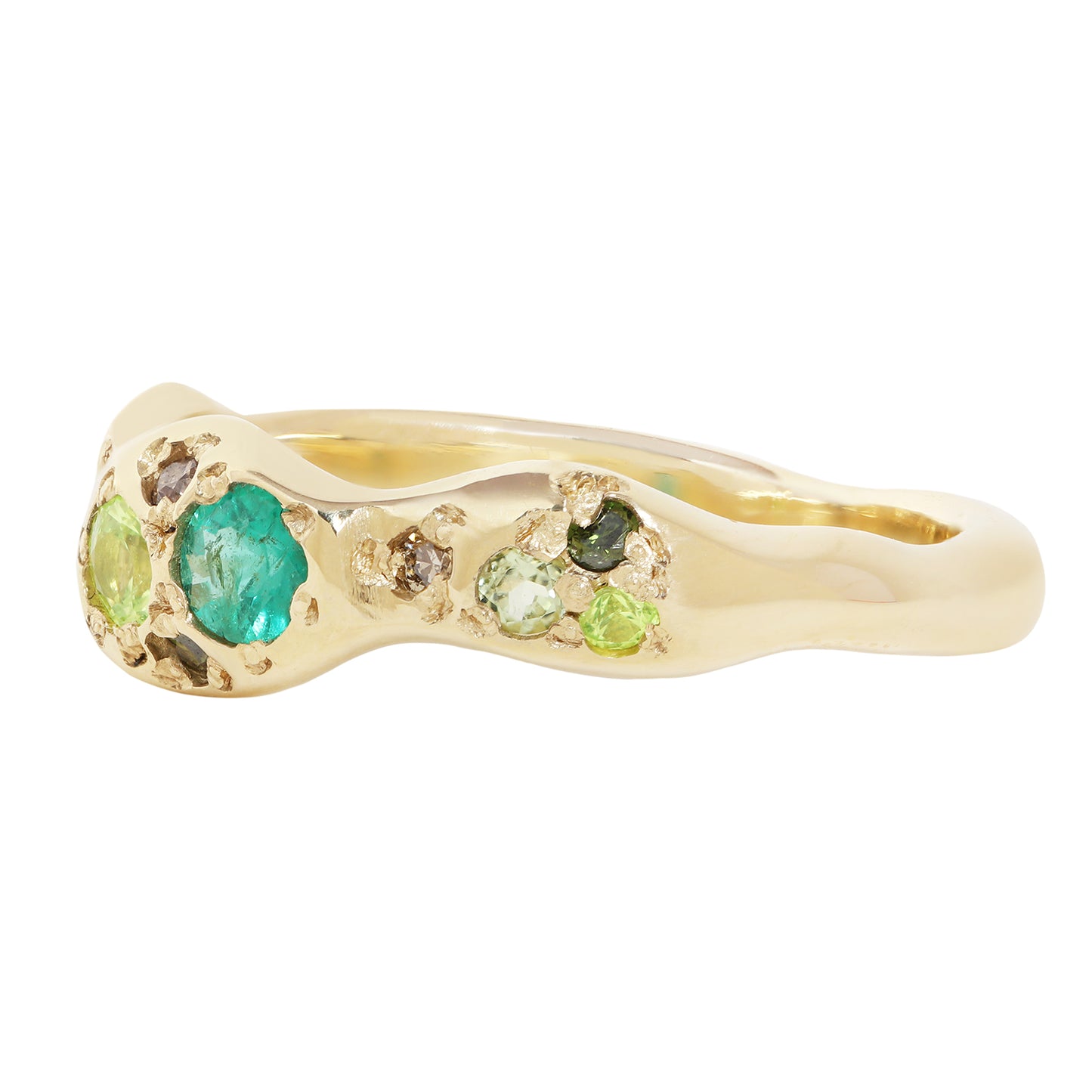A gold ring with a wavy, organic shape, featuring a large round green emerald and smaller green and brown stones, set against a plain white background.