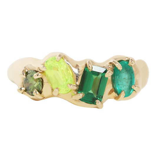 A gold wave-style ring featuring four green gemstones of varying shapes and sizes set in a row, shown against a plain white background.
