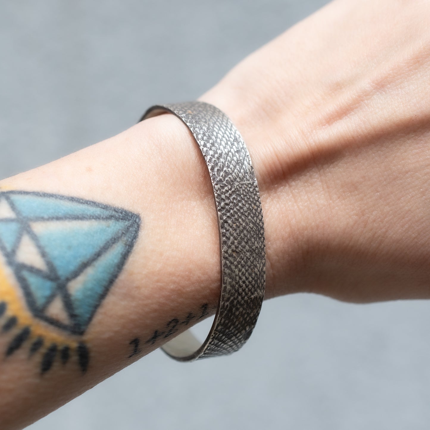 An oxidzed silver bangle with snakeskin texture pictured on the wrist - Lauren Wolf Jewelry | ESQUELETO 