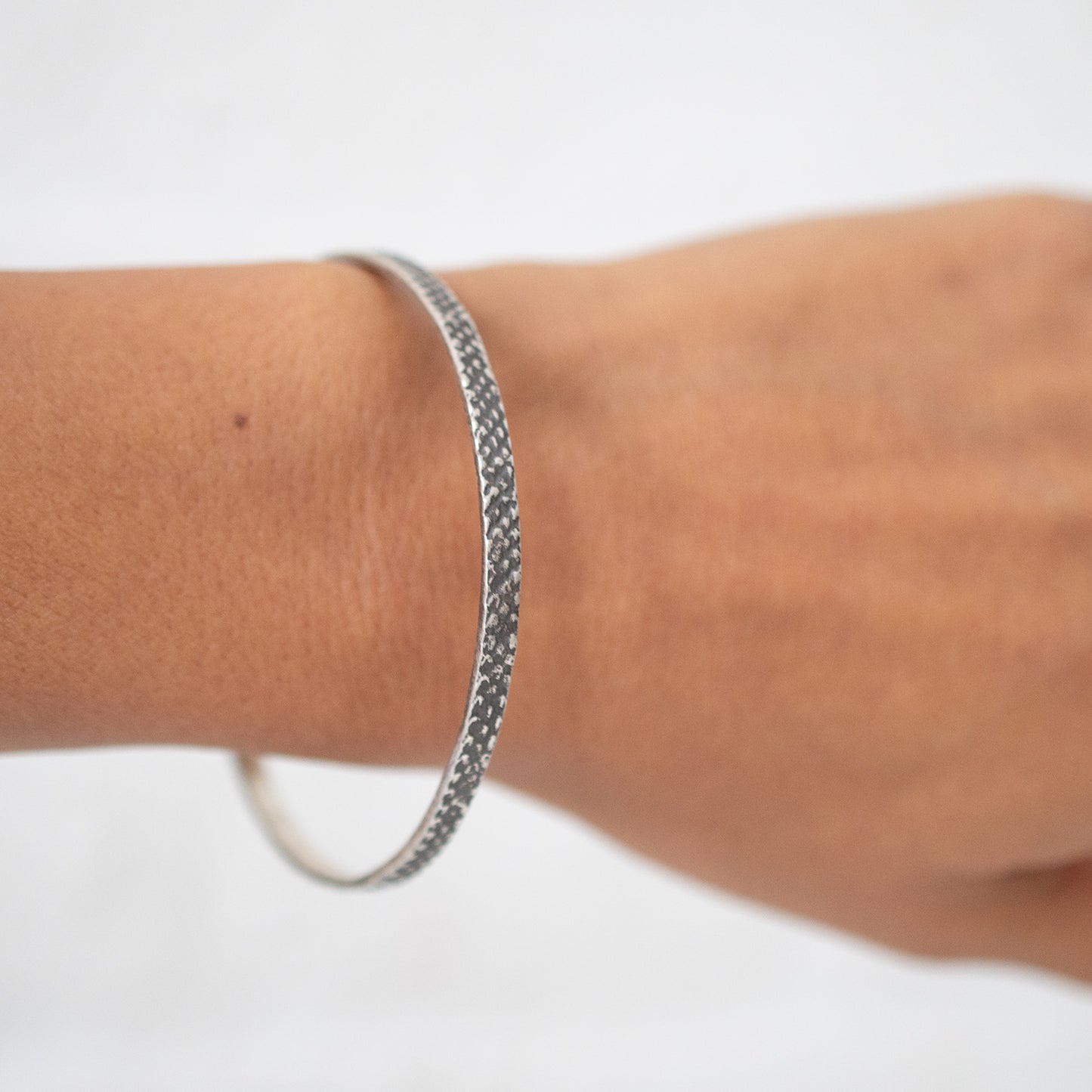 silver bangle with textured, oxidized finish worn on the wrist - Lauren Wolf Jewelry | ESQUELETO