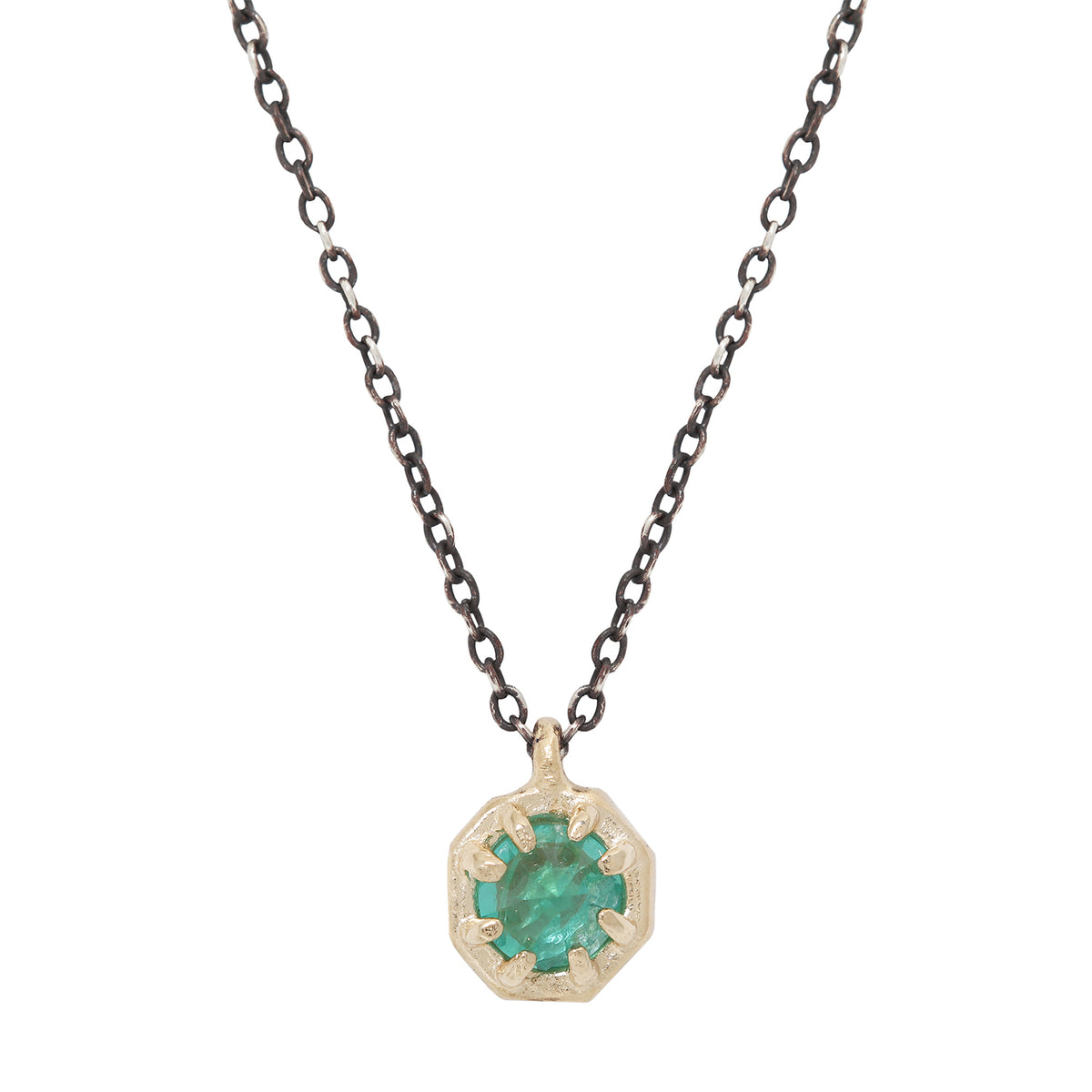 Emerald pendant set in gold on an oxidized silver chain against a white background