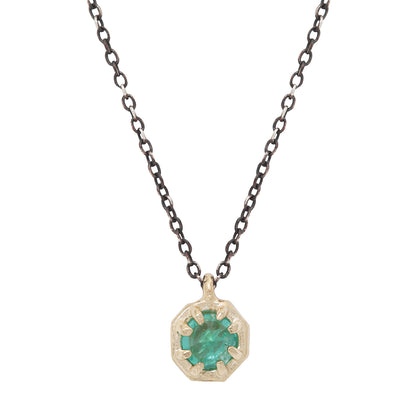 Emerald pendant set in gold on an oxidized silver chain against a white background