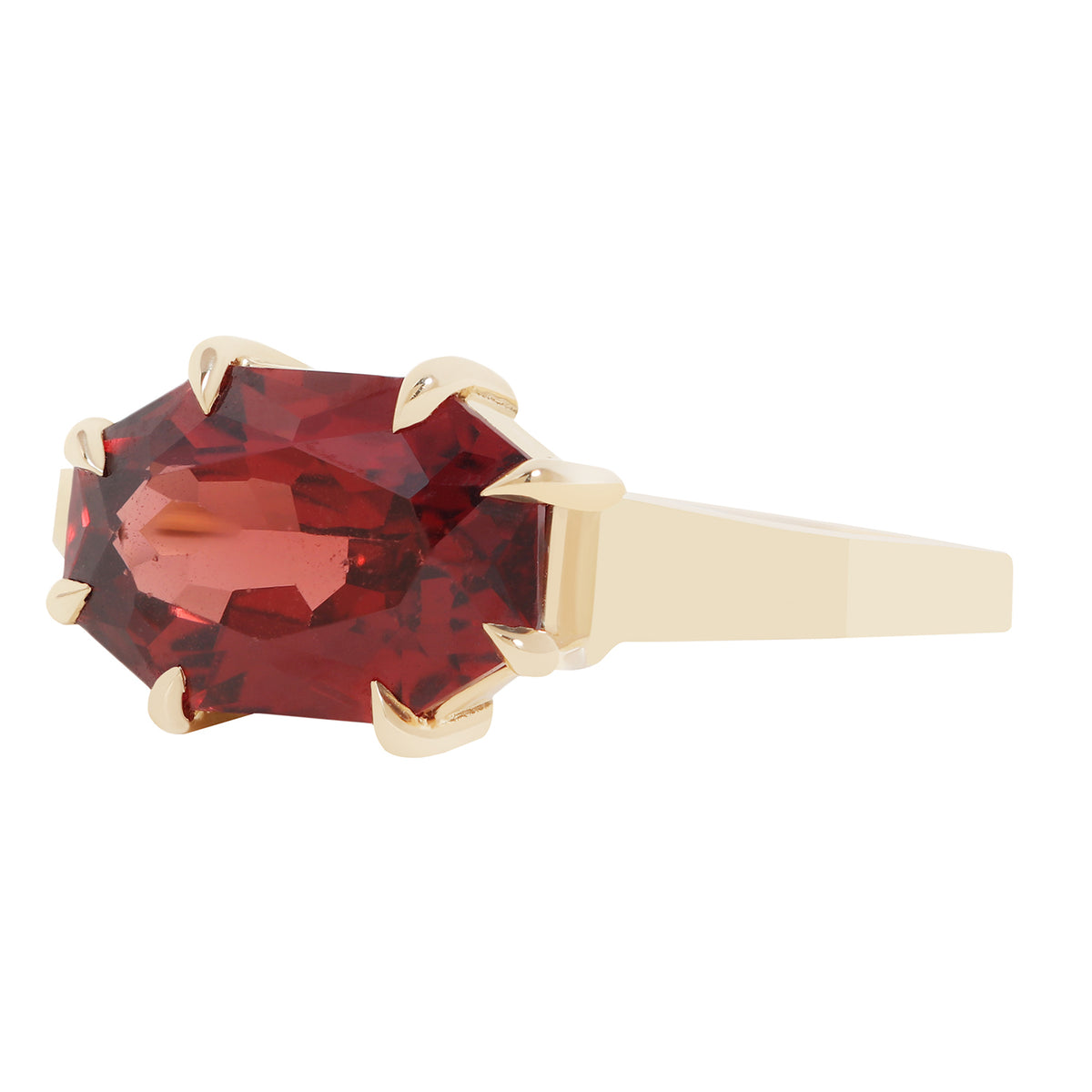 An oval-cut red gemstone ring set in a yellow gold prong setting with a gold band, shown against a plain white background.