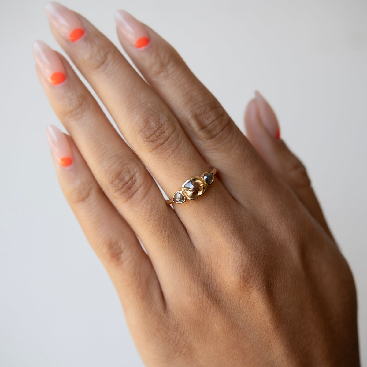 Hand wearing a gold ring with small stones on a plain background