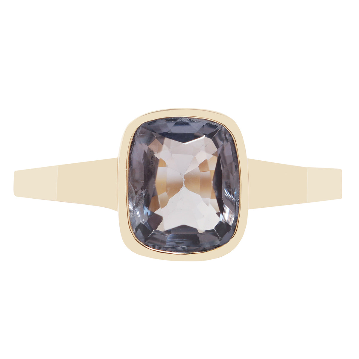 Bezel set solitaire yellow gold ring with a dark blue spinel rectangular stone on white background. 