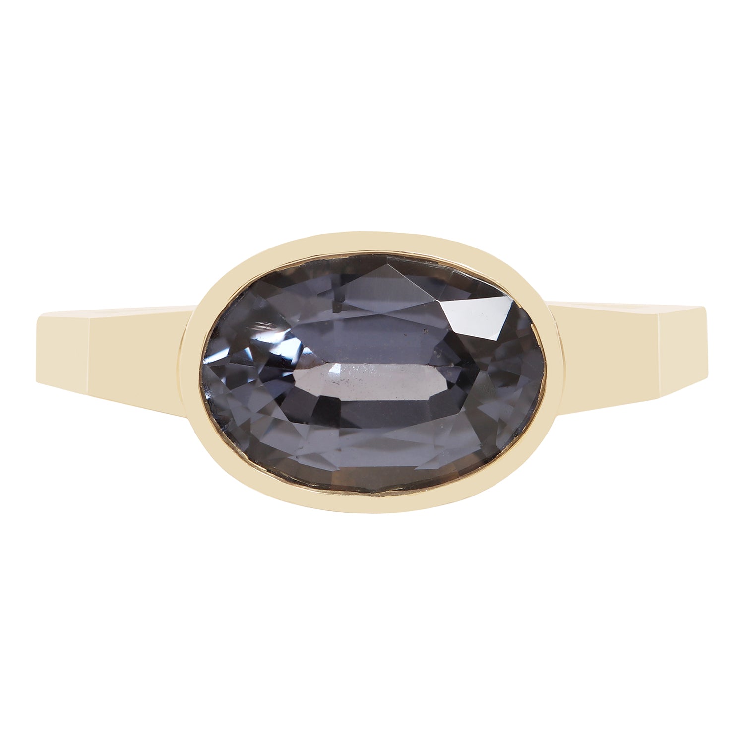 A gold ring featuring a large, faceted oval dark blue gemstone, presented on a clean white background.