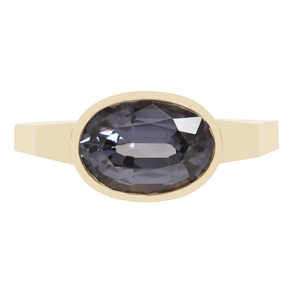 A gold ring featuring a large, faceted oval dark blue gemstone, presented on a clean white background.