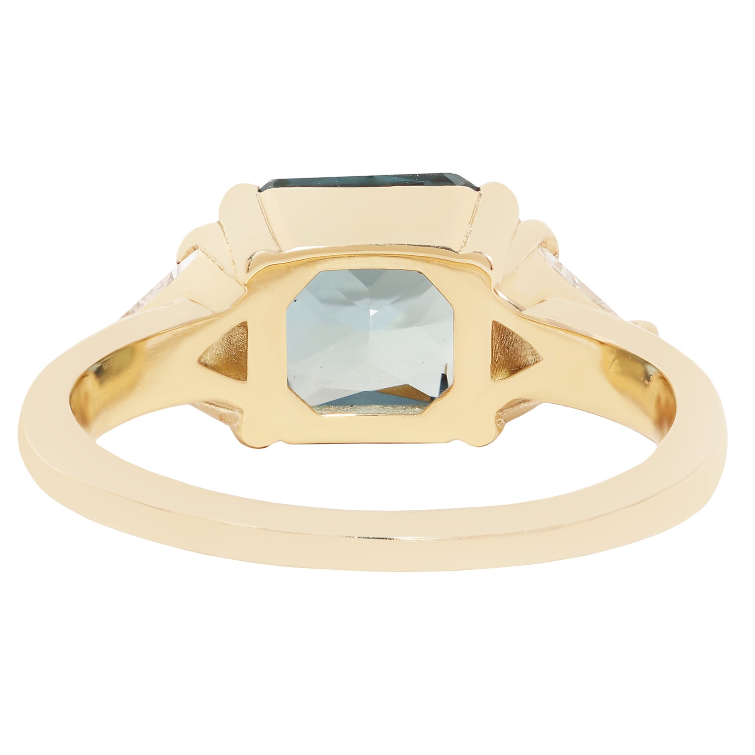 A gold signet ring featuring a large, faceted light blue-gray rectangular gemstone, with smaller clear stones set in the shoulders, shown on a plain white background.