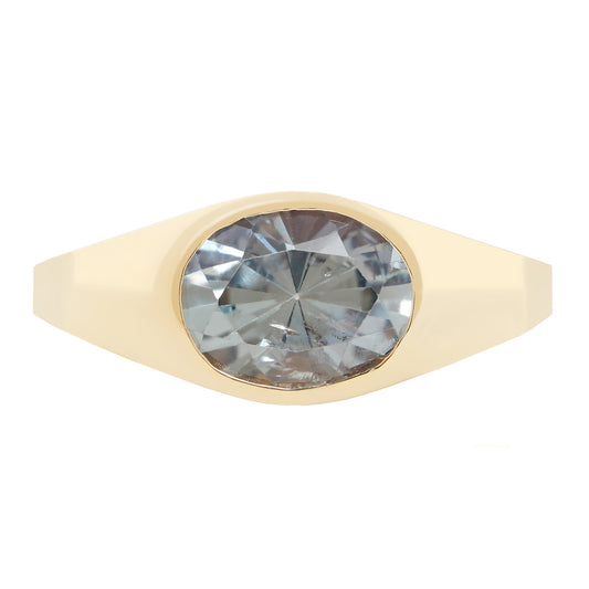 A yellow gold signet ring featuring a large, oval-cut light blue-gray gemstone, shown against a plain white background.