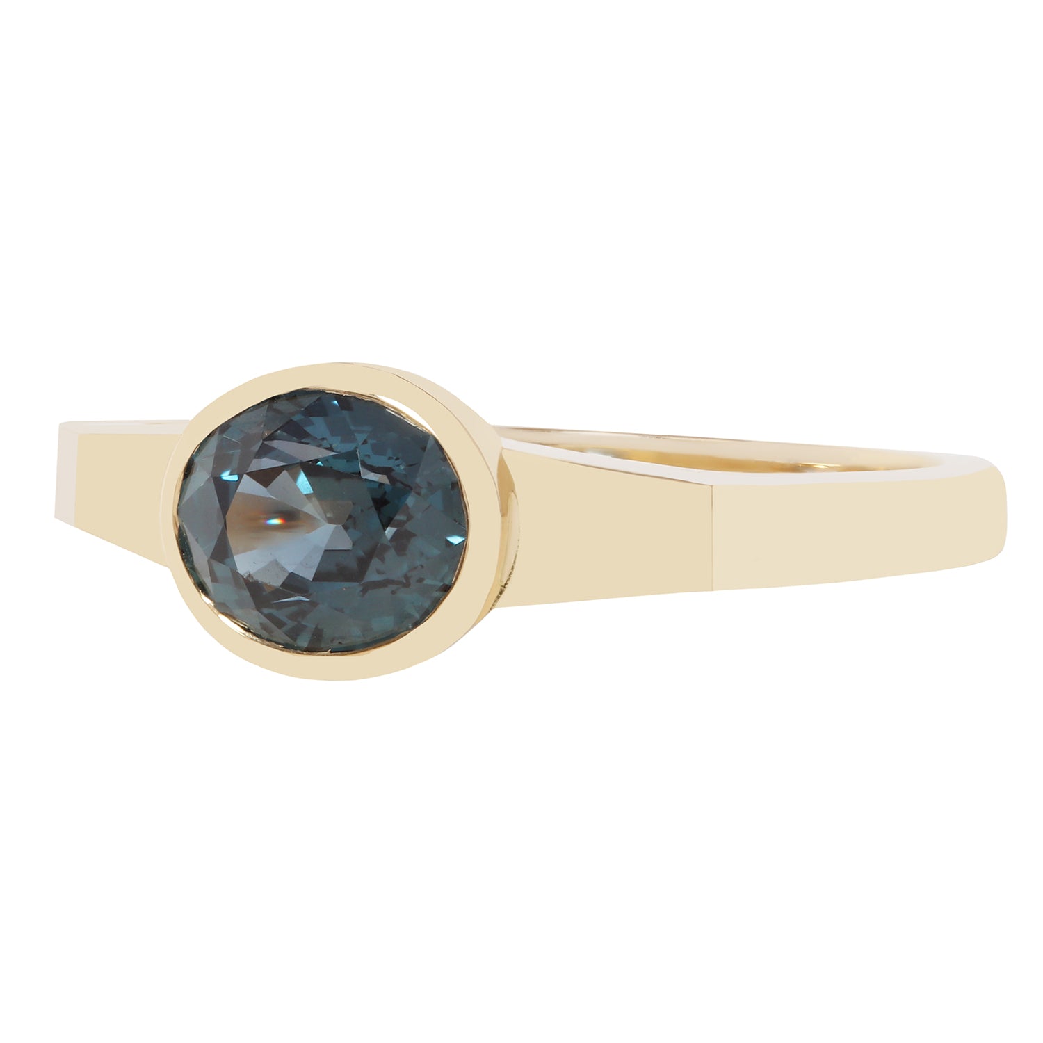 A yellow gold ring featuring a bezel-set oval faceted dark blue gemstone, shown against a plain white background.