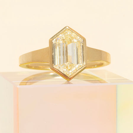 Gold ring with a diamond on a light pink background