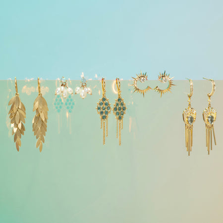 Collection of gold earrings on a gradient blue and green background
