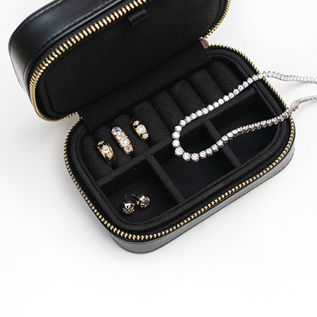 Black ESQUELETO jewelry case with gold and diamond jewelry on a white background