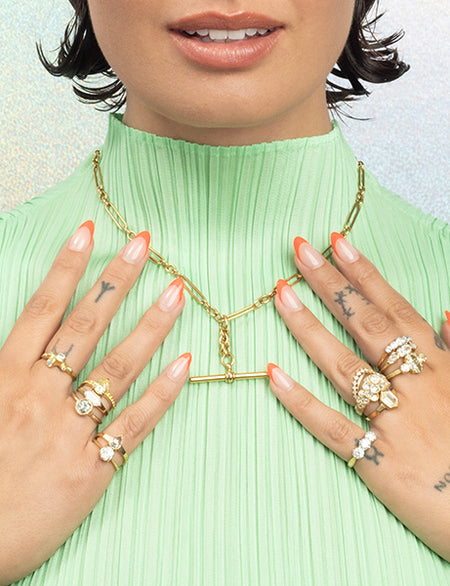 Person wearing gold jewelry including an antique and vintage necklace and multiple gold and diamond rings, with a light green top.