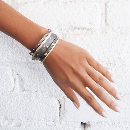 Rene Escobar - Hand wearing multiple bracelets on a textured white background