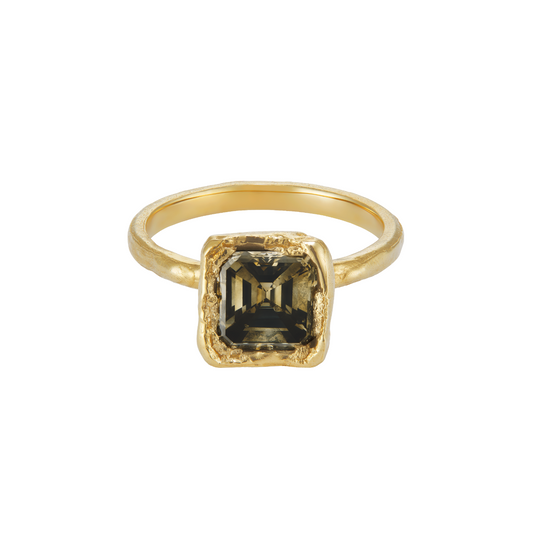 A gold ring featuring a square-cut dark smoky gemstone in a textured bezel setting, shown against a plain white background.