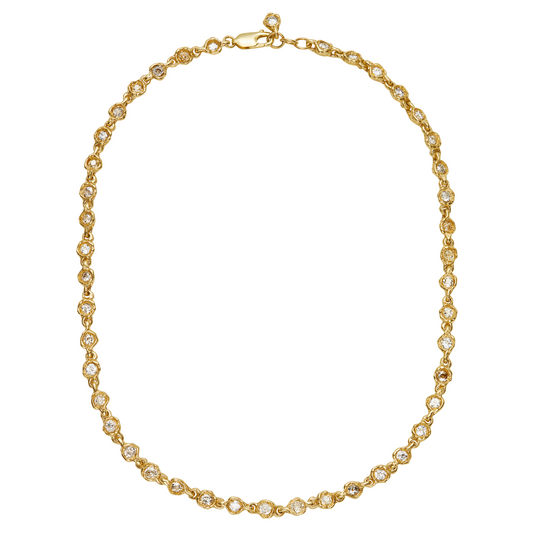 A gold tennis necklace with small clear gemstones set in each link, arranged in an oval shape on a plain white background.