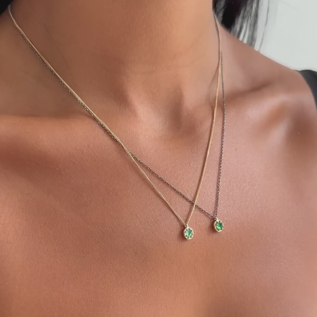 Video of two emerald pendants set in gold one an oxidized silver chain and another on a gold chain on person 