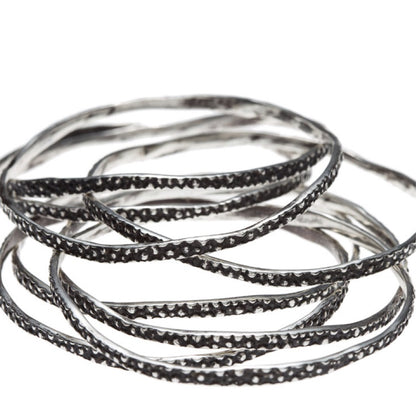 A stack of Silver Stingray Bangles by Lauren Wolf Jewelry shown on a white background