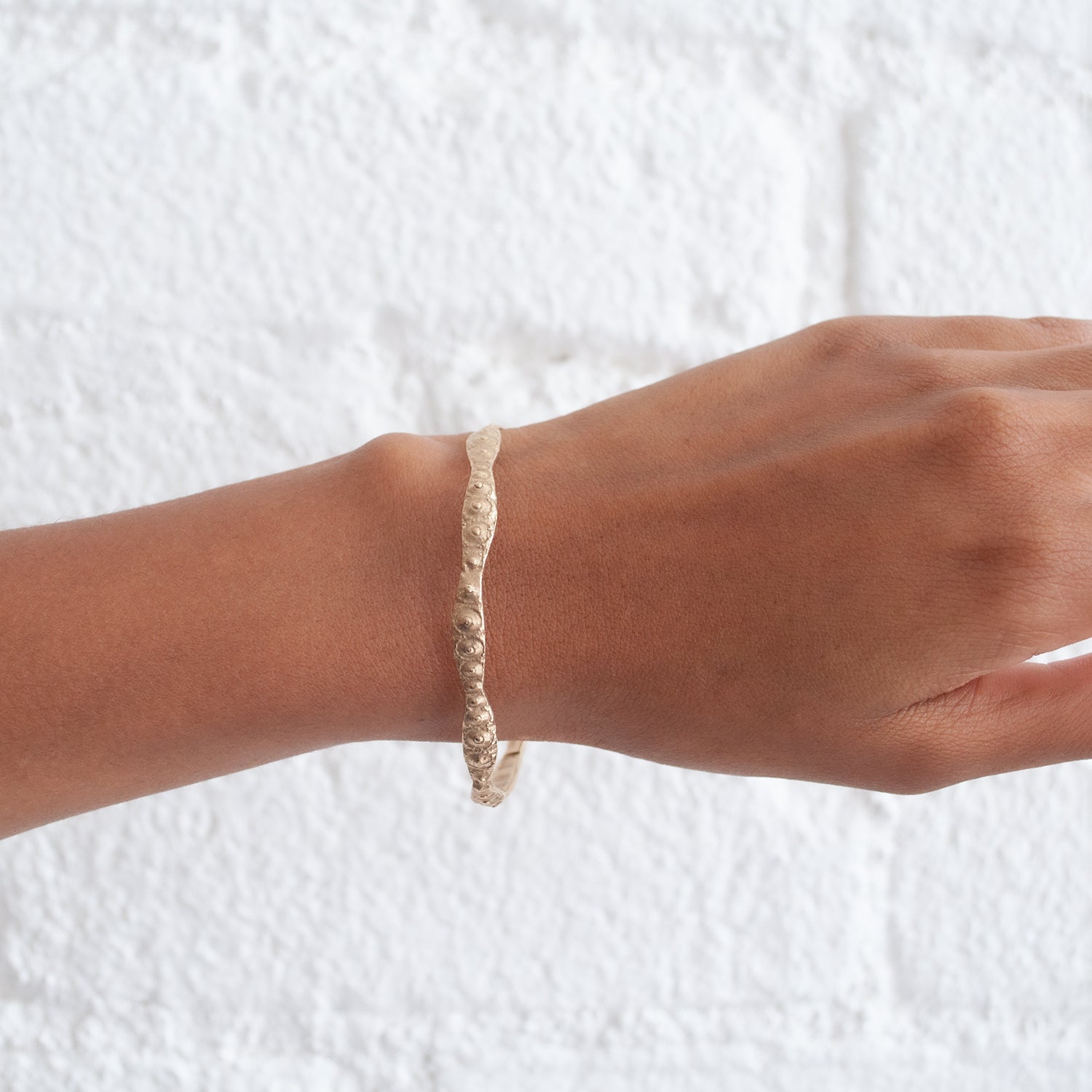 Sea urchin textured gold bangle from Lauren Wolf pictured on a wrist | ESQUELETO 