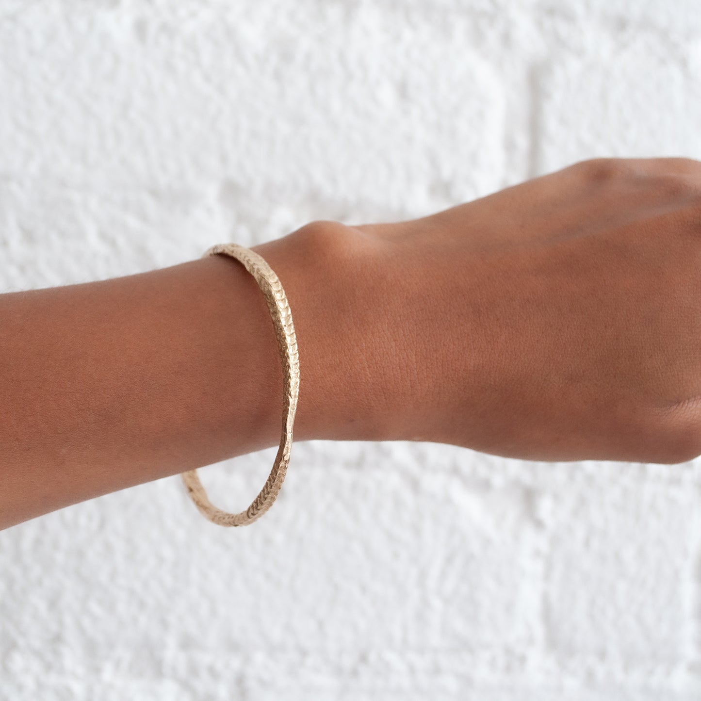 Textured gold bangle on a wrist against a white background - Lauren Wolf Jewelry | ESQUELETO