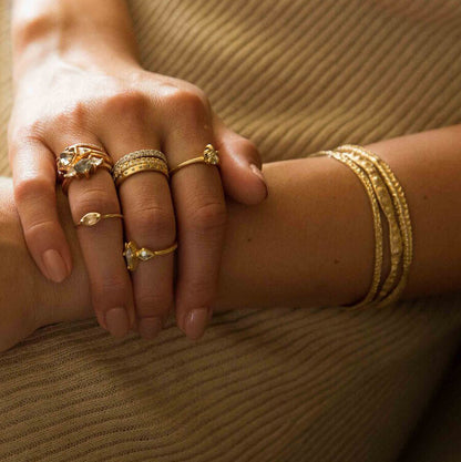Sea urchin textured gold bangle from Lauren Wolf pictured on a wrist with other gold bangles from the artist | ESQUELETO 